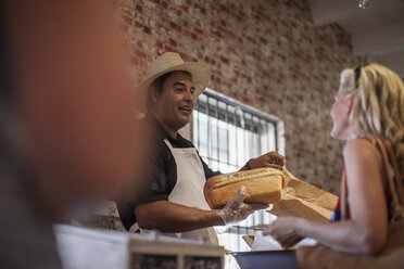 Shopkeeper in shop helping client, white bread - ZEF008789