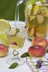 Peach iced tea in carafe, lemon, ice, mint leaves and peaches - YFF000552