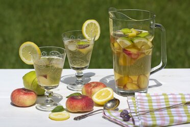 Peach iced tea in carafe, lemon, ice, mint leaves and peaches - YFF000553