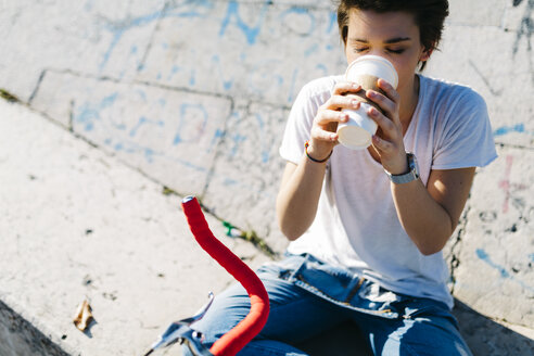 Junge Frau trinkt Kaffee aus einem Einwegbecher - GIOF001226
