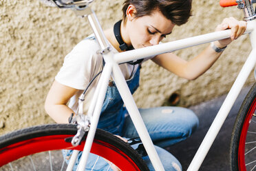 Junge Frau hockt am Fahrrad - GIOF001246