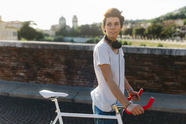 Young woman pushing bicycle on bridge - GIOF001250