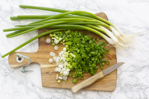 Chopped and whole spring onions on wooden board - SARF002781