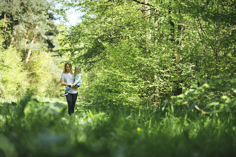 Mutter trägt Tochter im Wald, lizenzfreies Stockfoto