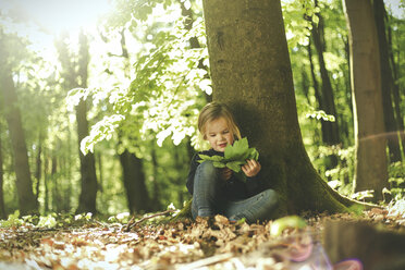 Girl in forest examining leaves - SBOF000152