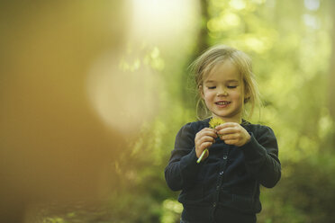 Girl in forest examining dandelion - SBOF000156