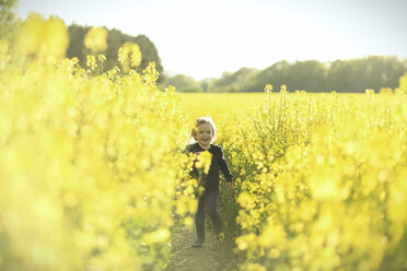 Happy girl running in canola field - SBOF000165