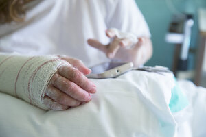 Frau im Krankenhaus, operierte Hand, benutzt Handy, linke Hand - ERLF000179