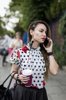 Portrait of young woman with coffee to go telephoning with smartphone - MAUF000664