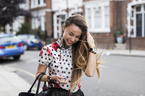 UK, London, Porträt einer lächelnden jungen Frau mit wehendem Haar, lizenzfreies Stockfoto