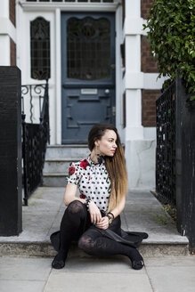 UK, London, young woman sitting on step of pavement - MAUF000669