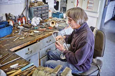 Instrumentenbauer bei der Reparatur einer Trompete in der Werkstatt - DIKF000201