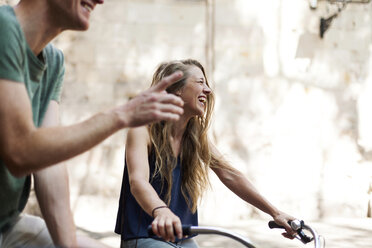 Lachende Frau mit Fahrrädern an der Seite ihres Partners - VABF000593