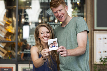 Glückliches Paar zeigt Selfie von ihrer Hochzeit vor einem Café - VABF000613