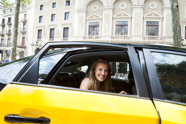 Spanien, Barcelona, glückliche junge Frau schaut aus dem Fenster eines Taxis - VABF000620