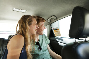 Lachendes Paar sitzt im Taxi und schaut durch das Fenster - VABF000622