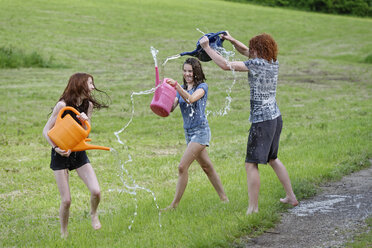 Drei Teenager mit Gießkannen, die mit Wasser spritzen - LBF001442