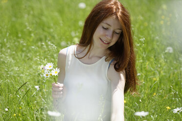 Redheaded teenage girl picking flowers on a meadow - LBF001446