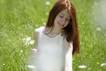 Rothaarige Teenagerin pflückt Blumen auf einer Wiese - LBF001446