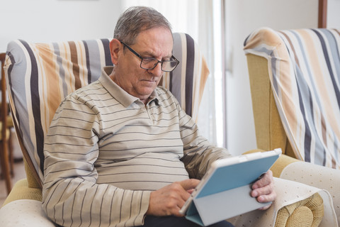 Älterer Mann zu Hause mit digitalem Tablet, lizenzfreies Stockfoto