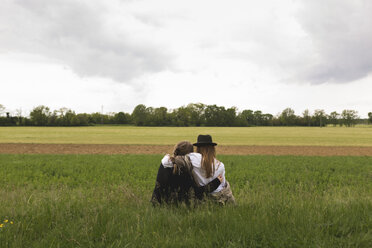 Rückenansicht von zwei Freunden, die auf einer Wiese in der Natur sitzen - BOYF000420