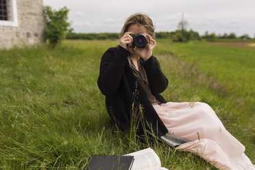 Woman sitting on a meadow taking picture of viewer - BOYF000446