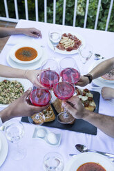 Freunde stoßen bei einem sommerlichen Abendessen mit Lambrusco-Wein an - ABZF000725