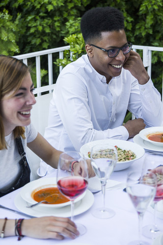 Junger Mann und Frau lächelnd bei einem Abendessen im Sommer, lizenzfreies Stockfoto