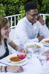 Junger Mann und Frau lächelnd bei einem Abendessen im Sommer - ABZF000732