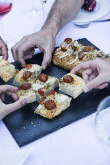 Die Hände nehmen ein Stück Focaccia während eines Sommeressens - ABZF000734