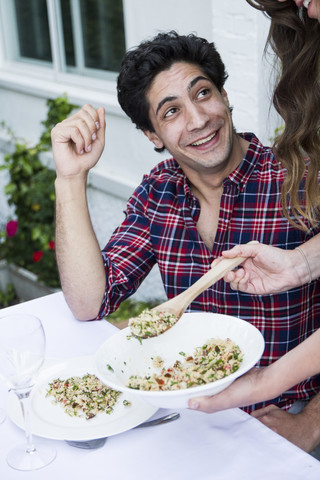 Frau serviert ihrem Gast Tabbouleh bei einem Sommeressen, lizenzfreies Stockfoto