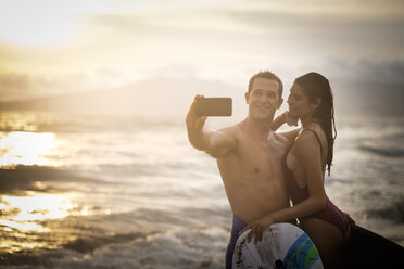Junges Paar macht ein Selfie am Strand in der Dämmerung - ABAF002058