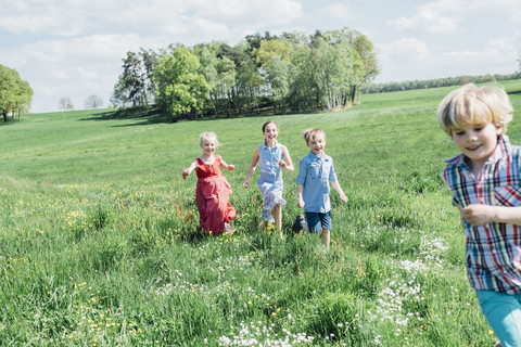 Glückliche Kinder rennen und spielen auf einer Wiese, lizenzfreies Stockfoto