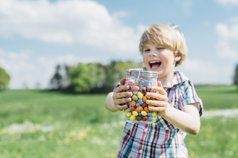 Glücklicher Junge im Freien, der ein Glas mit Jelly Beans hält, lizenzfreies Stockfoto