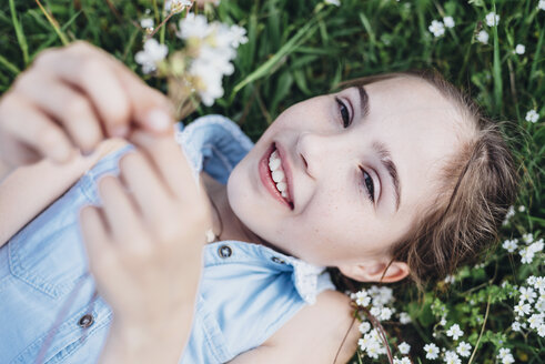 Lächelndes Mädchen in Blumenwiese liegend - MJF001925