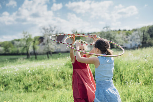 Zwei Mädchen mit Hula-Hoop-Reifen auf einer Wiese - MJF001932