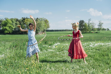 Zwei Mädchen mit Hula-Hoop-Reifen auf einer Wiese - MJF001933