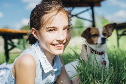 Porträt eines lächelnden Mädchens mit Hund auf einer Wiese, lizenzfreies Stockfoto