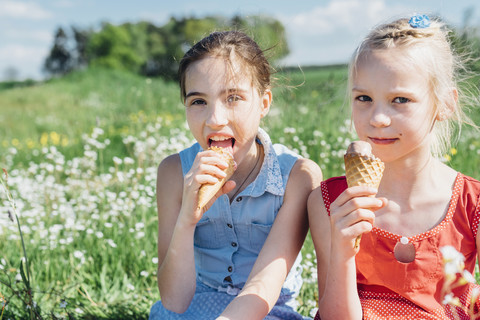 Zwei Mädchen auf einer Wiese essen Eistüten, lizenzfreies Stockfoto