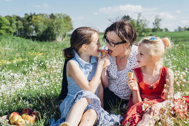 Mutter und zwei Mädchen auf einer Wiese, die Eistüten essen - MJF001954