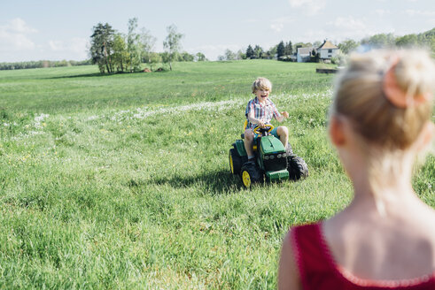 Junge fährt Spielzeugtraktor auf einem Feld - MJF001960