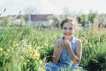 Smiling girl sitting in flower meadow - MJF001970