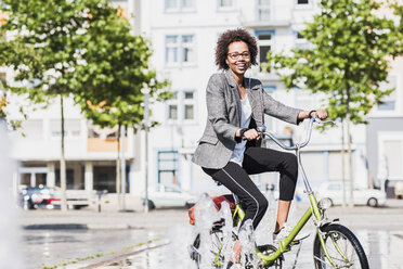 Porträt einer lächelnden Frau auf einem Fahrrad - UUF007754