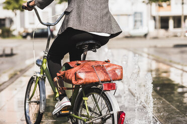 Back view of woman riding bicycle, partial view - UUF007755