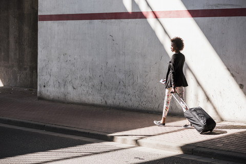 Geschäftsfrau mit Gepäck und Smartphone auf der Straße, lizenzfreies Stockfoto