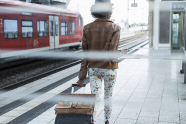 Back view of young woman with trolley bag and briefcase at platform - UUF007779