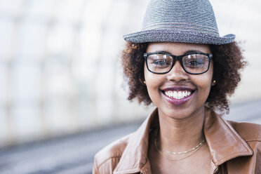 Porträt einer lächelnden jungen Frau mit Hut und Brille - UUF007782