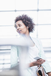 Young woman with earphones and smartphone watching something - UUF007793