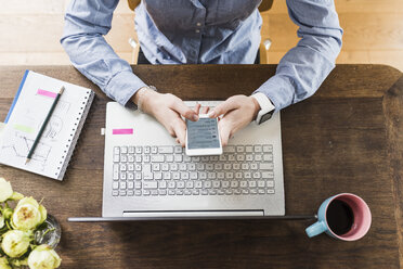 Teenage girl with celll phone and laptop at desk - UUF007823