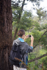 Indonesien, Java, Frau wandert in den Bergen und macht Fotos mit Smartphone - KNTF000389